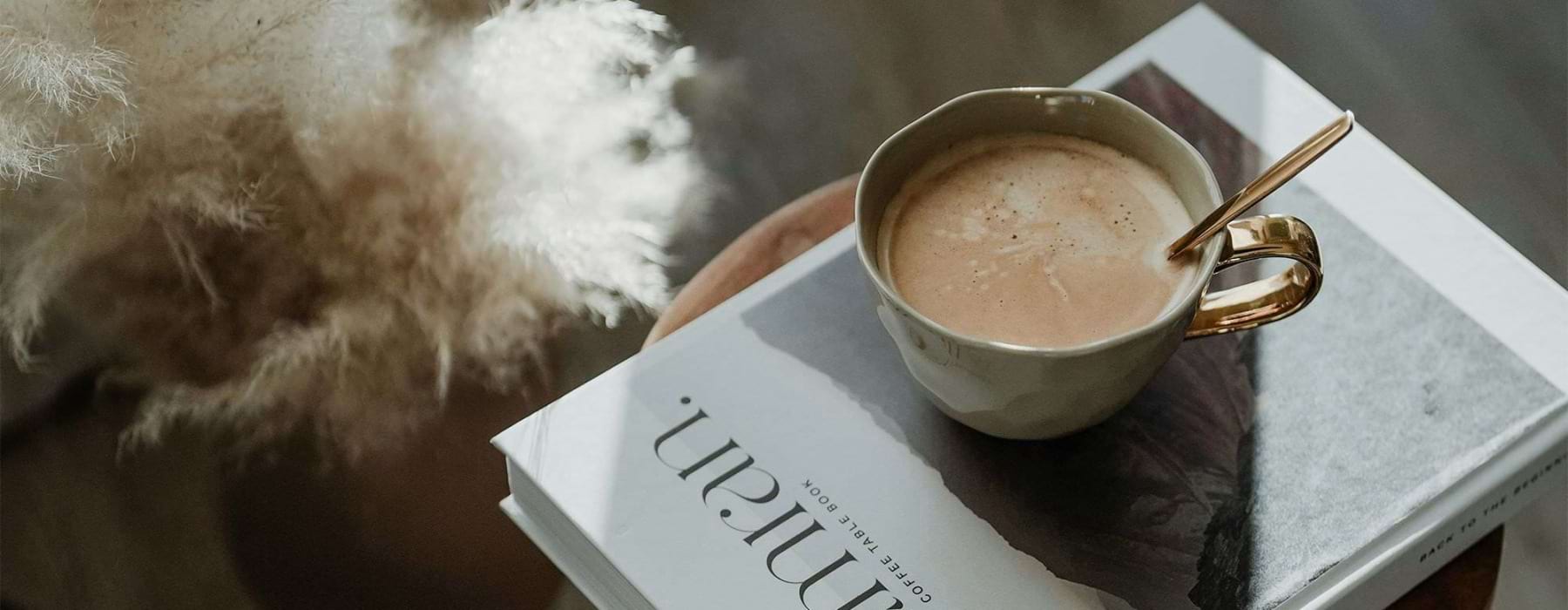 a cup of coffee on a book on a stool in a living room